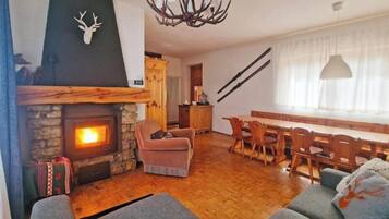 Una sala de estar acogedora con chimenea, un comedor con muebles de madera y una araña.