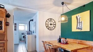 A dining area with a wooden table and chairs, a wall clock, and a green wall with a 'YEAH' sign. - Casa Polsa 1964 (Polsa)