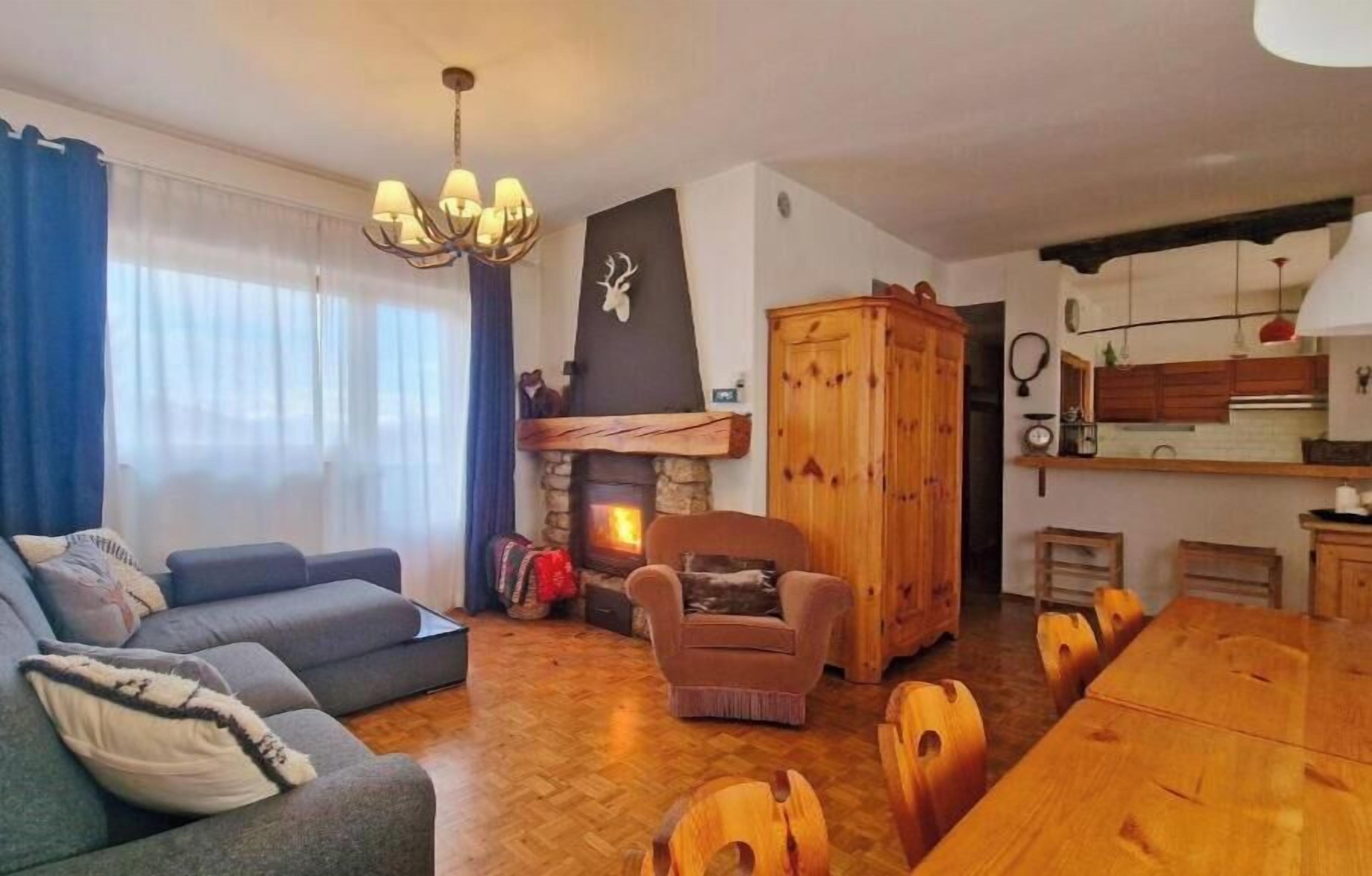 A living room with a fireplace, sofa, dining table, and wooden cabinet.