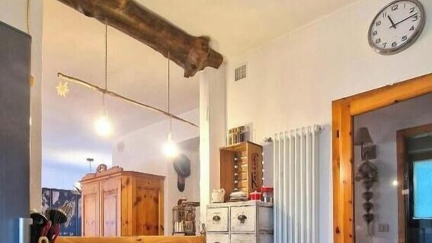 A kitchen with wooden cabinets, a hanging light fixture, a clock, and a radiator. - Casa Polsa 1964 (Polsa)