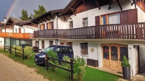 A chalet-style building with a balcony, a car parked in front, and a rainbow in the sky. - Casa Polsa 1964 (Polsa)