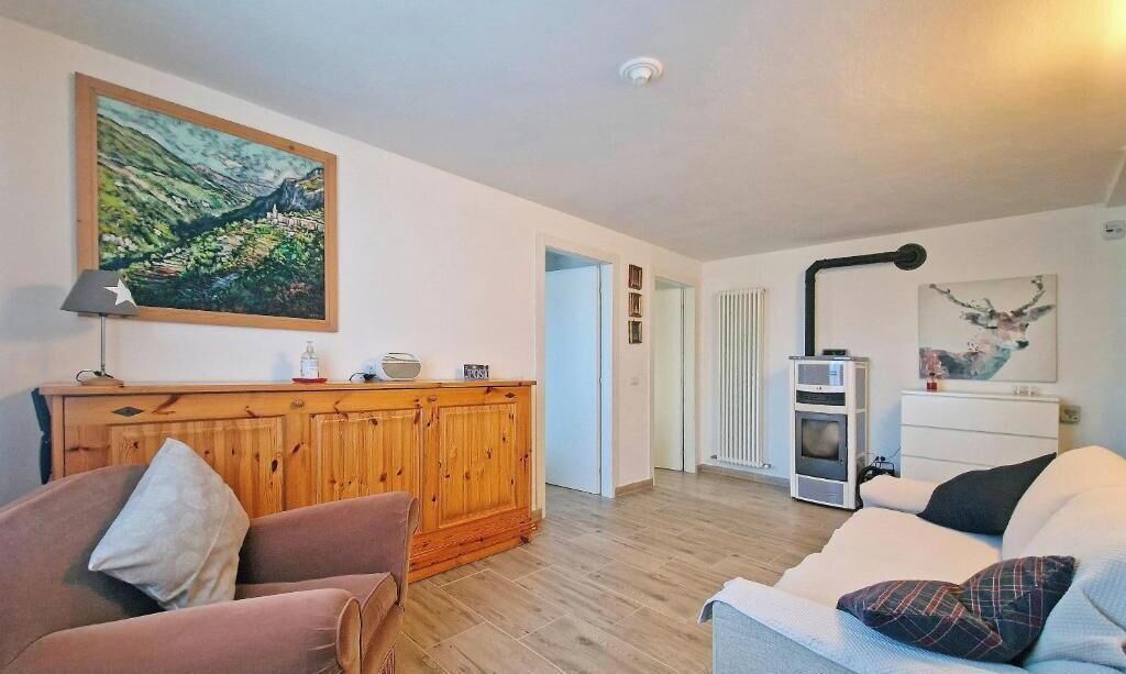 Una sala de estar con un mueble de madera, un sofá, una lámpara y un cuadro en la pared.
