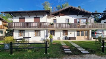 Ein zweistöckiges Gebäude mit Balkon, einem kleinen Garten und einem gepflasterten Weg.