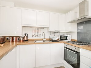 A modern kitchen with white cabinets, stainless steel appliances, and a wooden countertop. - Manor Heath Apartment 3 - Stunning Sea Views (Scarborough)