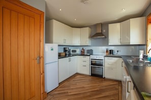 A kitchen with white cabinets, a stove, microwave, and a wooden door.