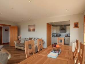 A dining area with a wooden table, chairs, and a bowl of fruit.