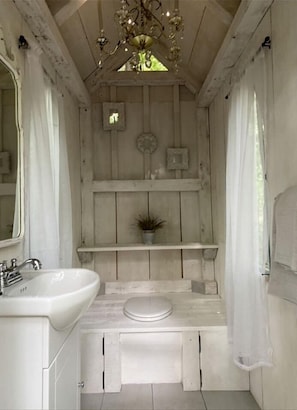 A rustic bathroom with a wooden vanity, a sink, a toilet, and a chandelier. - Luxurious Gazebo Nestled in Nature by Private Lake For Secluded Getaway, Ontario (Hastings)