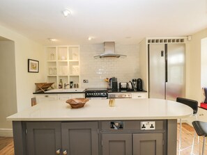 A modern kitchen with a central island, built-in cabinets, a stainless steel refrigerator, and a tiled backsplash. - Rose Cottage, Corsham, Wiltshire (Corsham)