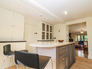 A kitchen with a white countertop, black chairs, and a wooden dining table. - Rose Cottage, Corsham, Wiltshire (Corsham)