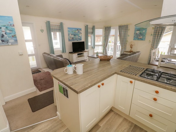 A compact kitchen with a central island, a dining area with a table and chairs, and a living room with a sofa.