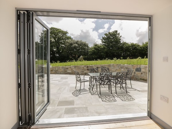 A sliding glass door leading to an outdoor patio with a stone wall, a table, and chairs.