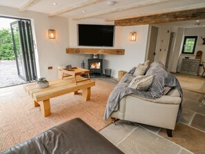 Ein gemütliches Wohnzimmer mit Kamin, einer Couch, einem Couchtisch und einem Fernseher, der über dem Kamin angebracht ist.