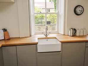 A kitchen with a sink, a window, a clock, and a coffee maker. - Snowdrop Cottage, Brompton-By-Sawdon (Scarborough)
