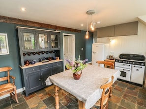 A kitchen with a dining table, cabinets, a refrigerator, and a stove. - Snowdrop Cottage, Brompton-By-Sawdon (Scarborough)
