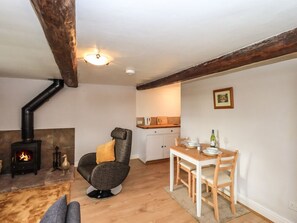 A cozy living room with a fireplace, a dining area with a table and chairs, and a kitchen with cabinets and a countertop. - The Duck House, Brampton, Cumbria (Carlisle)