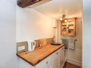 A compact kitchen with a wooden countertop, a kettle, a sink, and a wooden cabinet with glass doors. - The Duck House, Brampton, Cumbria (Carlisle)