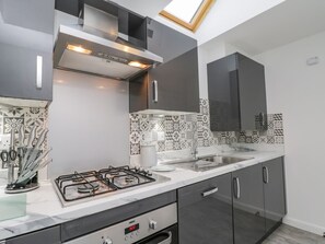 Une cuisine moderne dotée d’une cuisinière à gaz, de meubles en acier inoxydable, d’un crédence décorée et d’un puits de lumière.
