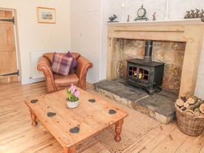 Una sala de estar acogedora con una chimenea de piedra, un sillón de cuero, una mesa de centro de madera y una cesta de mimbre.