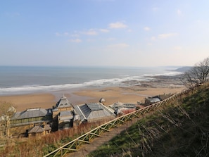 Un ensemble de bâtiments situé sur la côte, offrant une vue sur la plage, avec une promenade en bois et un ciel dégagé.