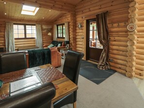 A log cabin interior with a dining table, chairs, a sofa, and a fireplace.