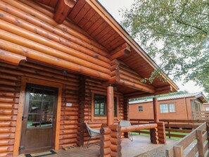 A log cabin with a porch, a bench, and a door.