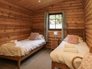 A log cabin room with two wooden beds, a nightstand, and a window with curtains. - Log Cabin near to Felton. WiFi (Morpeth)