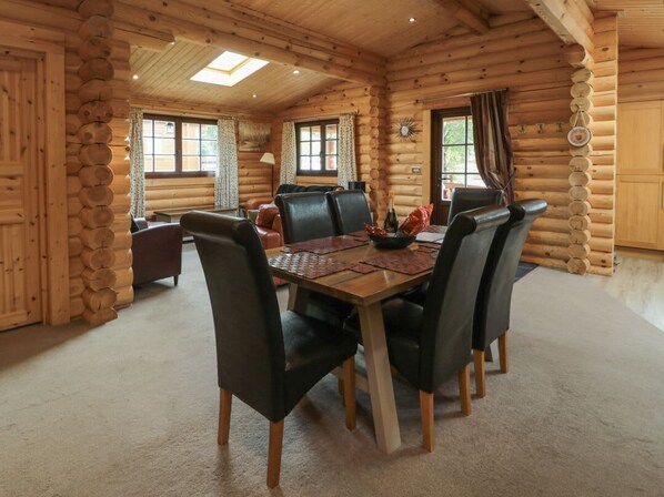A log cabin interior with a dining table, chairs, and a fireplace.