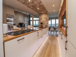 A modern kitchen with a central island, built-in appliances, and a view to the outside. - The Lodge @ Racecourse House, Holywell (Holywell)