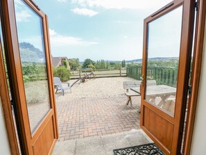 Eine Terrasse mit Pflasterboden, einer Holzbank und einem Tisch.
