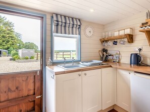 A kitchen with a window, wooden cabinets, a sink, and a kettle. - Charming The Nook Retreat in Louth (Louth)