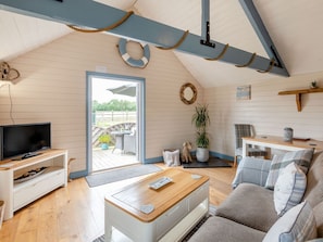A cozy living room with a television, sofa, coffee table, and a view of the outdoors. - Charming The Nook Retreat in Louth (Louth)
