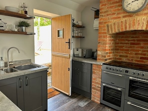 A compact kitchen with a brick oven, a refrigerator, and a sink.