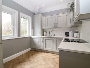 A modern kitchen with white cabinets, a microwave, and a window. - Park View Upper, in Llandudno. (Llandudno)