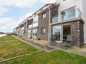 A row of modern townhouses with large windows, a grassy lawn, and a paved walkway. - Oakley View Apartment, Gwynedd (Porthmadog)