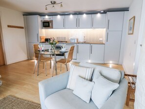 Eine moderne Küche mit grauen Schränken, einem Esstisch mit Stühlen und einem hellblauen Sofa im Vordergrund.