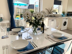 A dining table set with white plates, silverware, and a vase of white flowers. - 2 Boathouse Terrace in St Eval (Wadebridge)