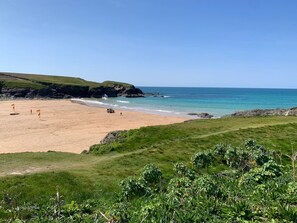 A beach with a clear sky, sandy shore, and grassy areas. - 2 Boathouse Terrace in St Eval (Wadebridge)