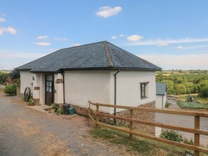 A single-story building with a sloped roof, a wooden fence in the foreground, and a gravel driveway. - Jack's Nest, South Molton (South Molton)
