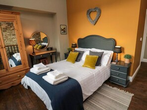 A bedroom with a bed, bedside tables, a dresser, a mirror, and a heart-shaped wall decoration.