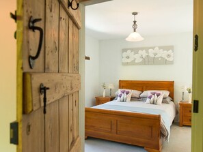 Ein Schlafzimmer mit einem hölzernen Bett, einem Nachttisch, einer Wandleuchte und einer Tür mit einer Nummer.