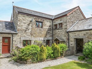 A stone building with multiple windows, a red door, and a gravel driveway. - Nightingale Cottage, Lostwithiel (Liskeard)