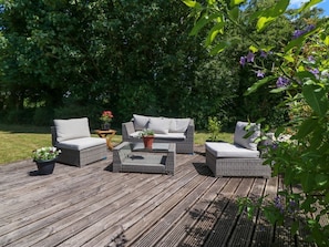 Eine Terrassendusche mit Korbmöbeln, einem Couchtisch in der Mitte und Pflanzentöpfen.
