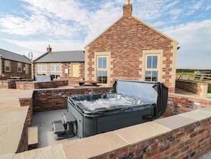 Una casa de ladrillo con jacuzzi, mobiliario exterior y cielo despejado.