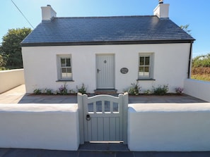 A white building with a dark roof, a front door, and a gate.