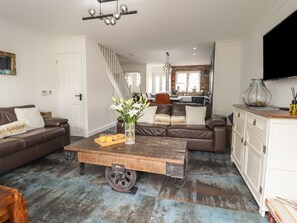 A living room with a brown leather sofa, a wooden coffee table, and a white cabinet. - Tritons Retreat, Sir Ynys Mon. (Moelfre)