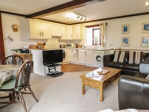 A living room with a TV, wooden coffee table, and a sofa. - Brunnion Cottage, St Ives (Hayle)