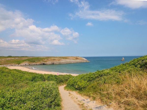 A coastal path leading to a beach with a clear view of the sea and a distant island. - Cranford Cottage: Cozy Retreat (Pembroke)