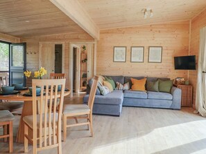 Un intérieur en bois comprenant un coin repas, un canapé et un téléviseur.
