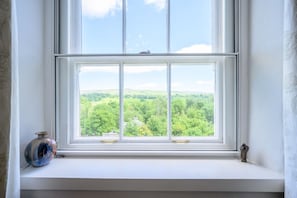 A window with a view of green hills and a clear sky.