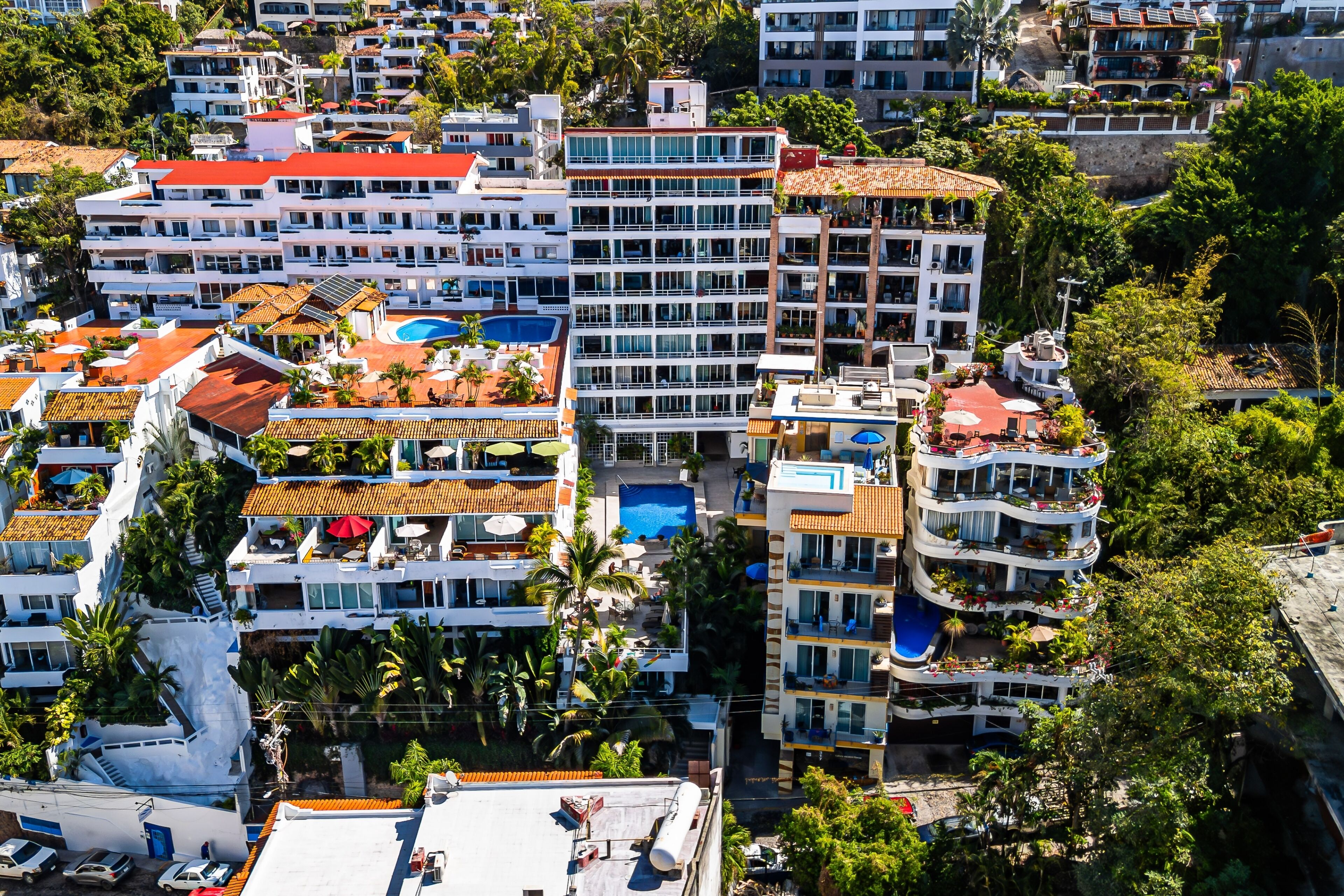 Un hôtel de grande hauteur doté de nombreux balcons, d’une piscine et entouré d’une végétation luxuriante.